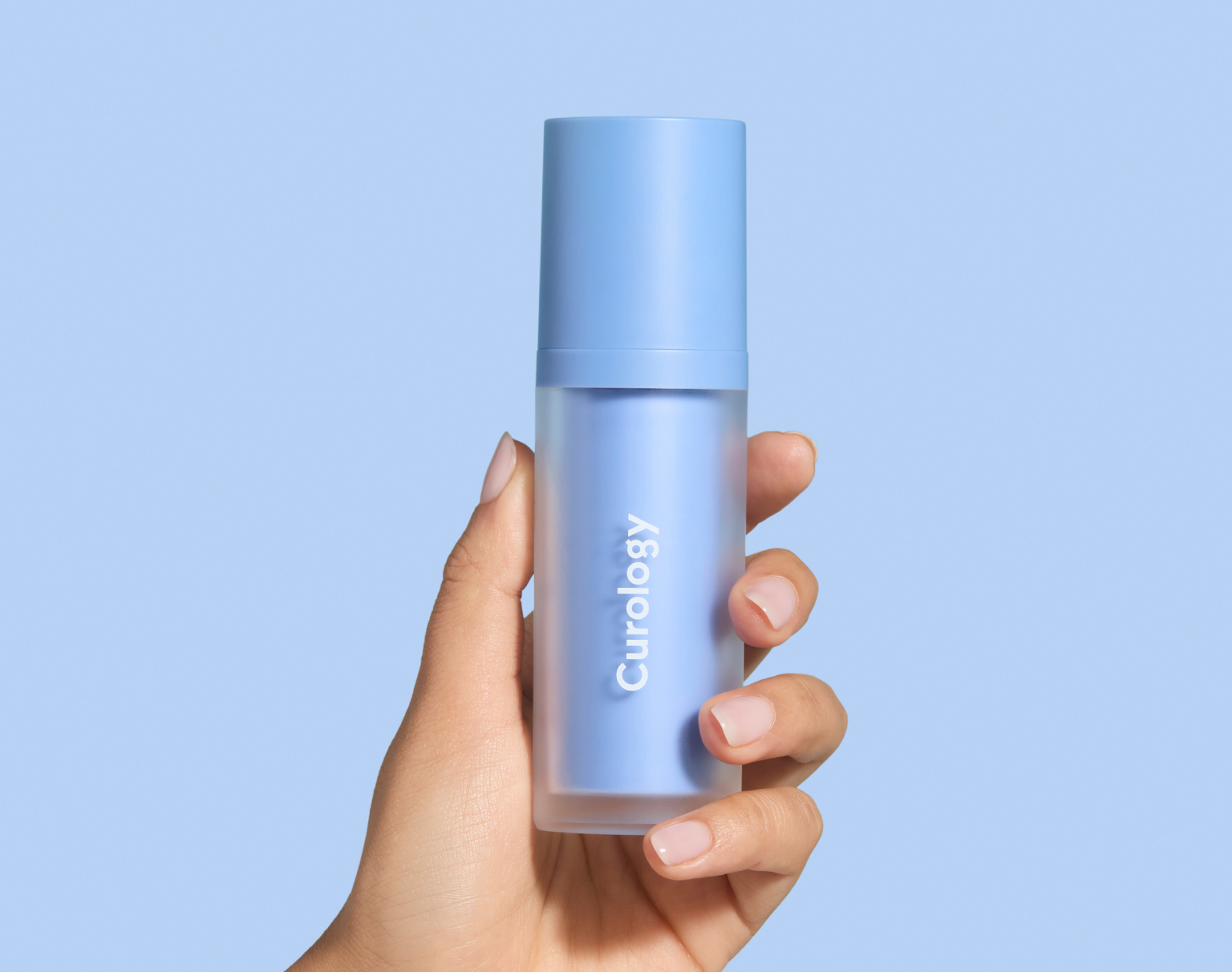 Hand holding Curology Dayprime Rx, a prescription daytime acne treatment designed to prep skin before sunscreen or makeup.