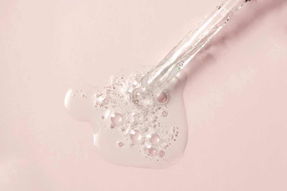 BHA acid drops from pipette on pastel pink background