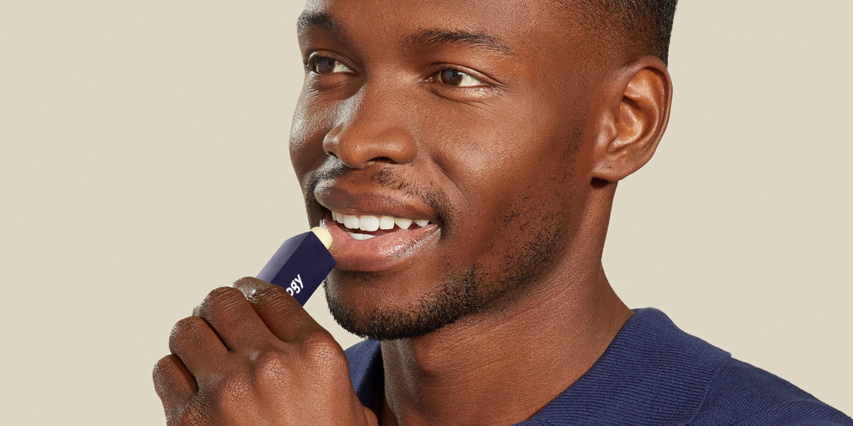 Man applying moisturizing lip balm to lips