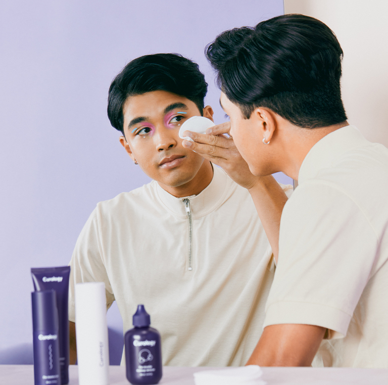 Image of man using micellar water to remove makeup from face 