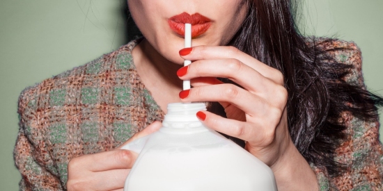 Woman with red lipstick drinking milk from a straw