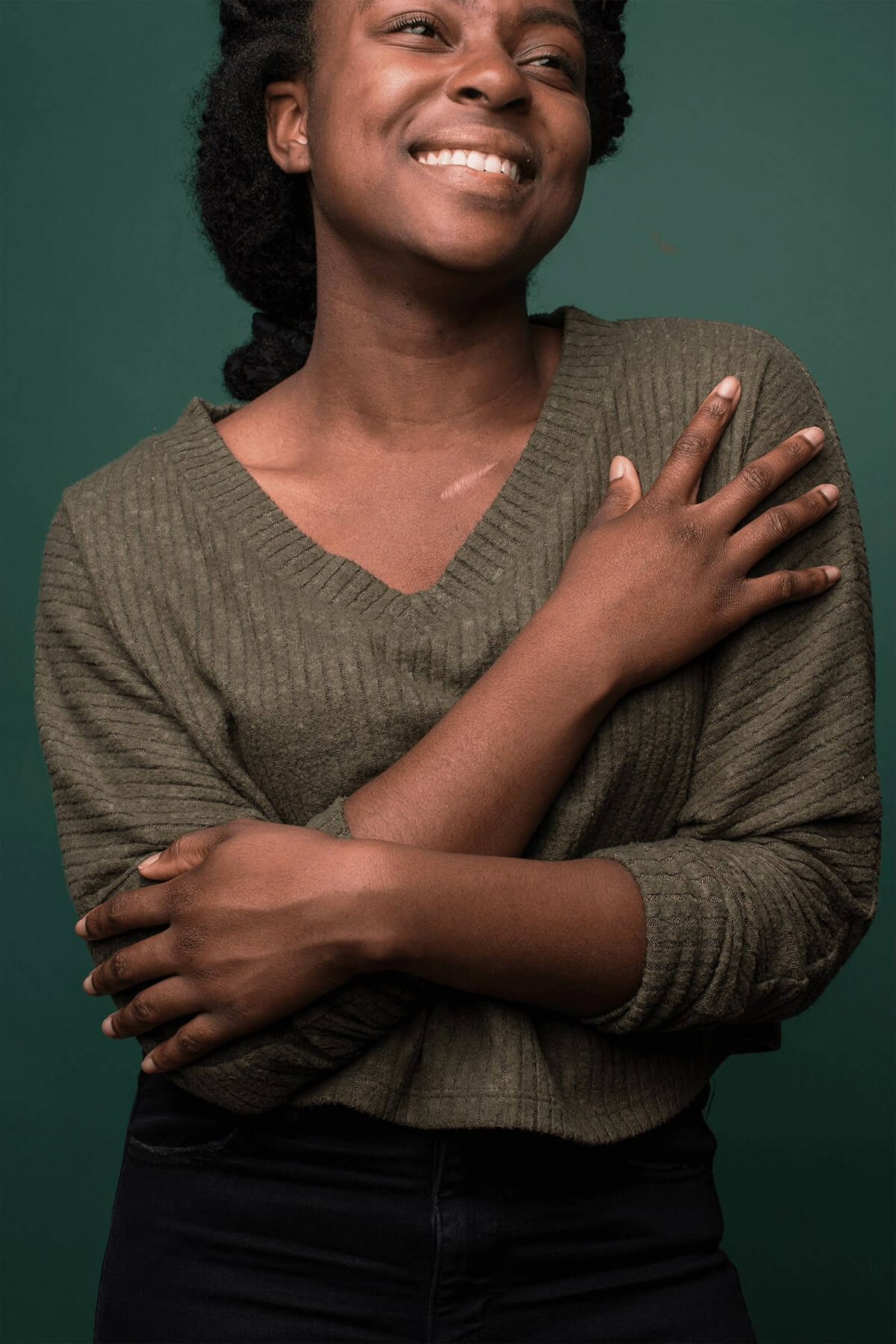 Woman smiling with arms crossed with a green background