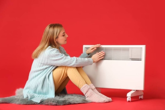 Woman Sitting Next to Electric Heater