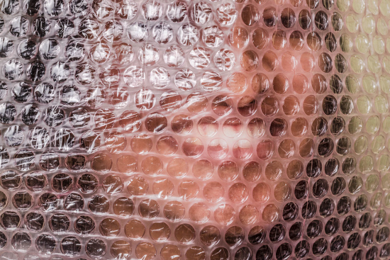 Closeup of woman's face behind bubble wrap