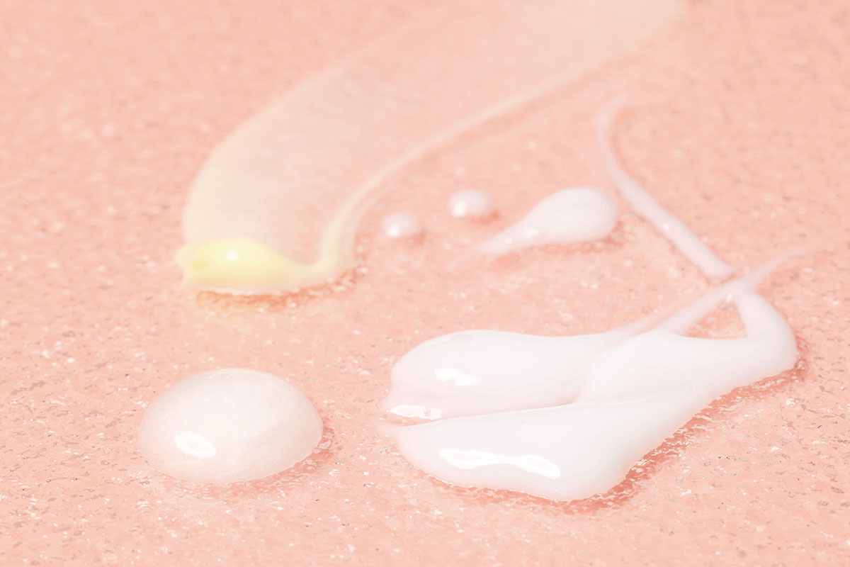 Extreme close-up of swatches on plexiglass of 3 different kinds of skincare product textures