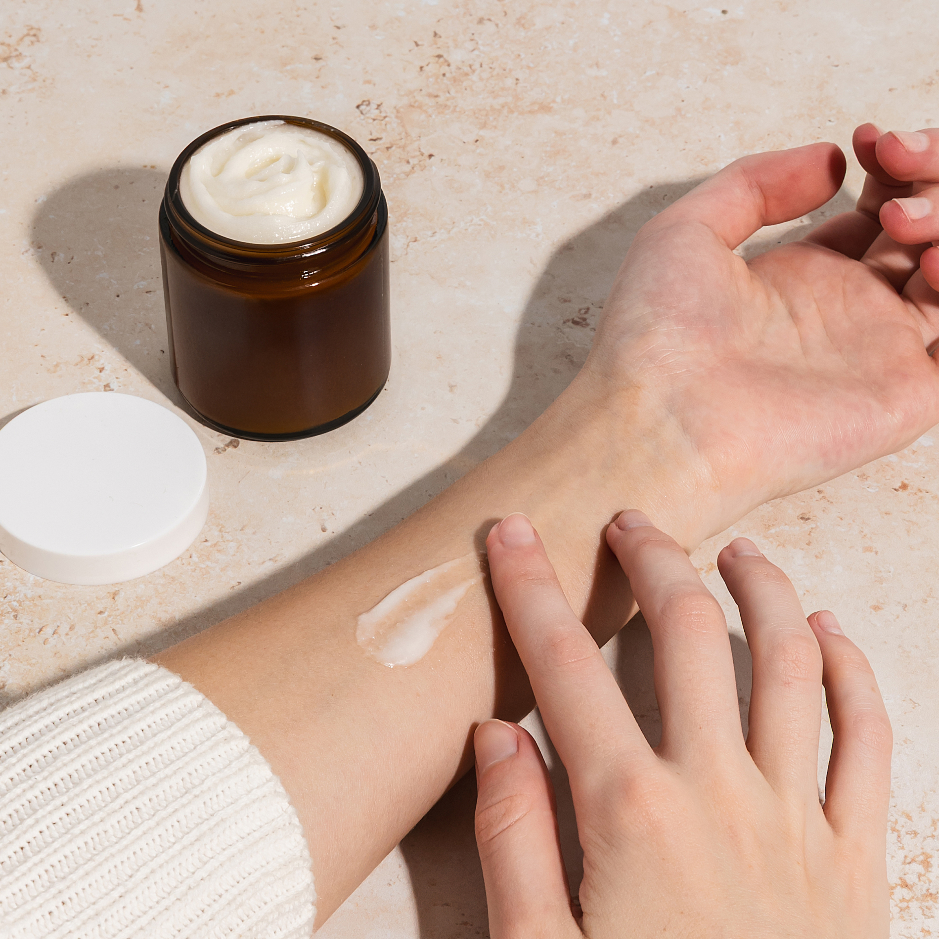 Person applying beef tallow from a jar; Curology dermatology providers say unregulated tallow may introduce bacterial contamination and oxidation.