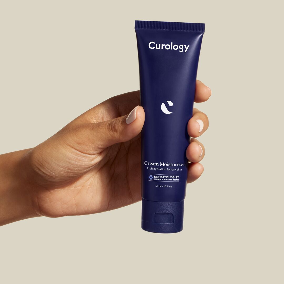 A hand holding Curology Cream Moisturizer product