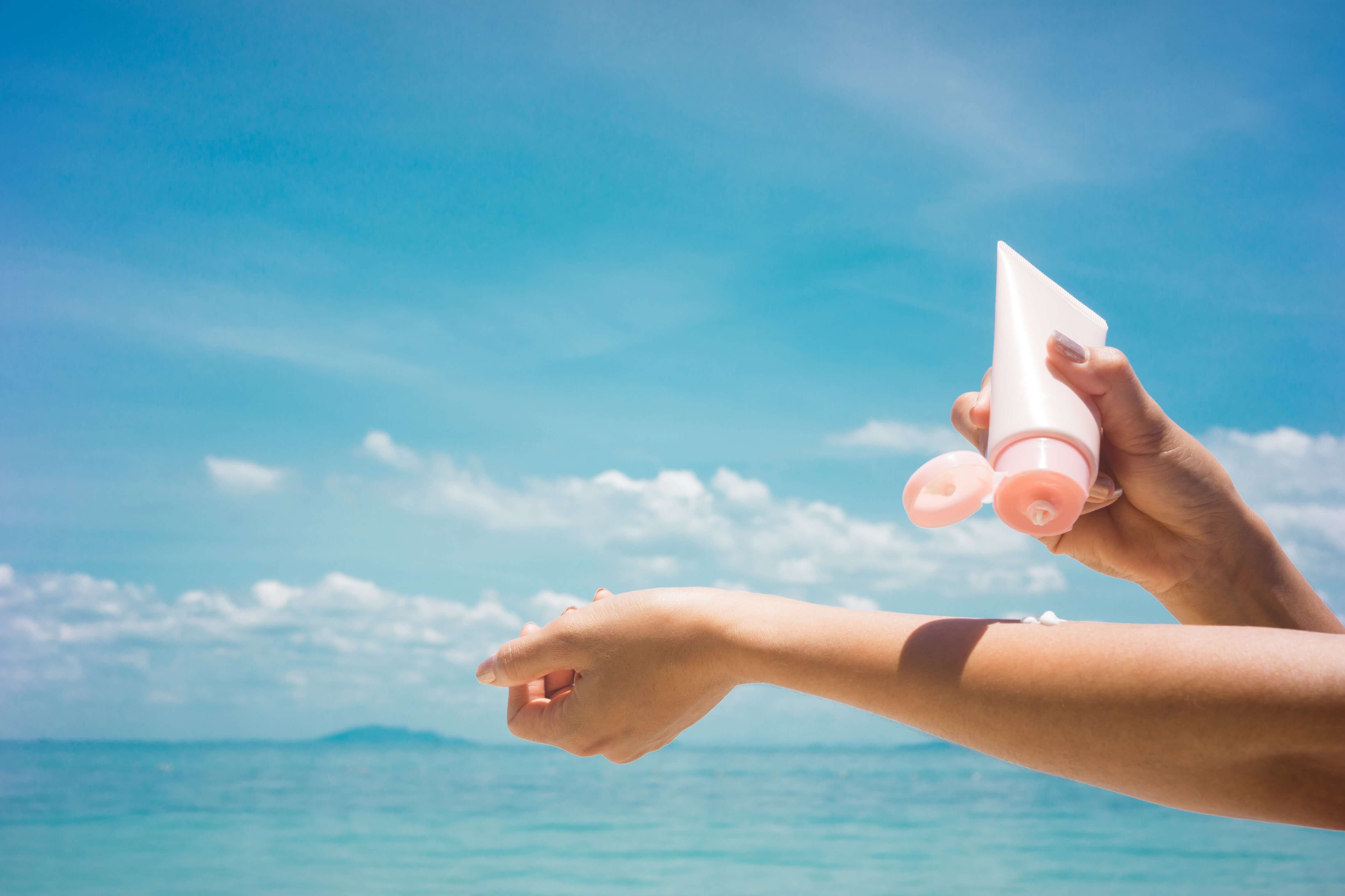 Woman applying sunscreen on her body at the beach