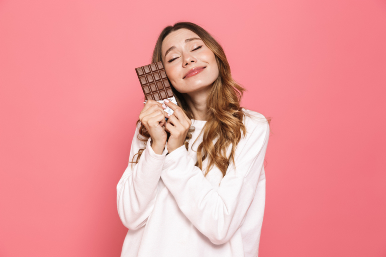 Happy young woman hugging chocolate - Does chocolate cause acne? 
