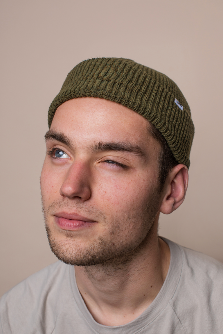 Man with green beanie with one eyes closed