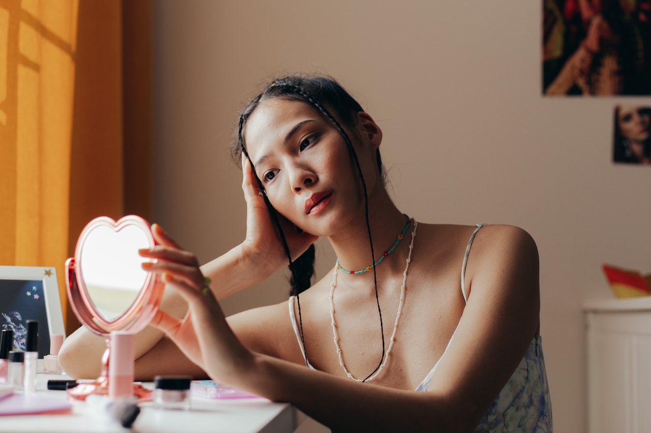Woman looking at her skin on a little mirror