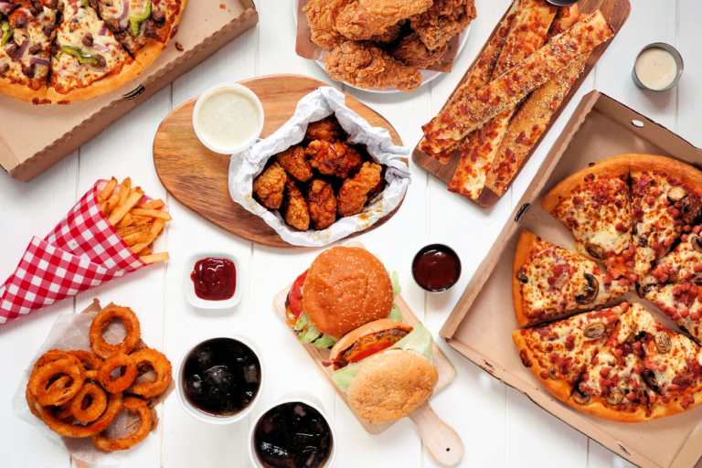 Image of pizza, hamburgers, fried onion rings and chicken wings assorted fast food favorites