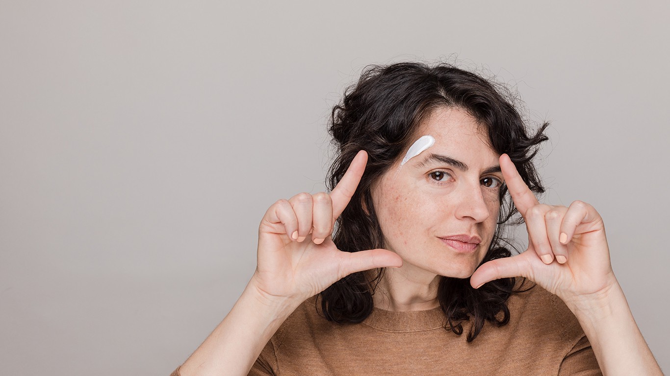 Woman holding fingers up to make frame with skincare cream