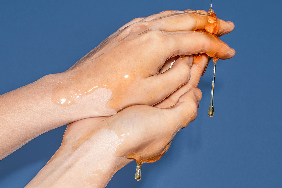 Closeup of hands with golden liquid over them