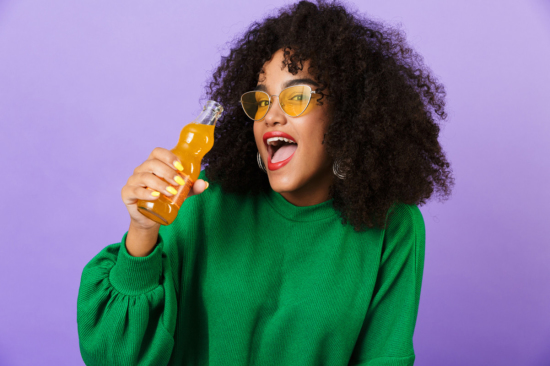 woman holding orange soda while smiling