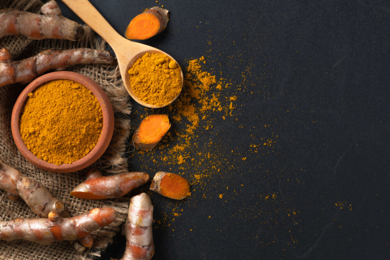 Turmeric powder and root on black background