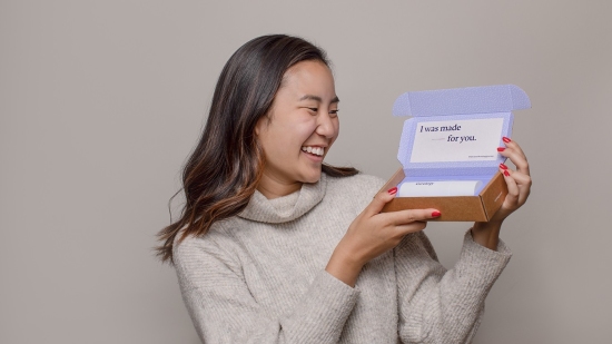 Woman holding Curology box saying "I was made for you"