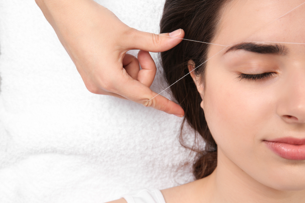 Young woman having professional eyebrow hair removal