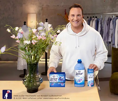 Lächelnder Mann mit der Lenor Aprilfrisch-Produktreihe