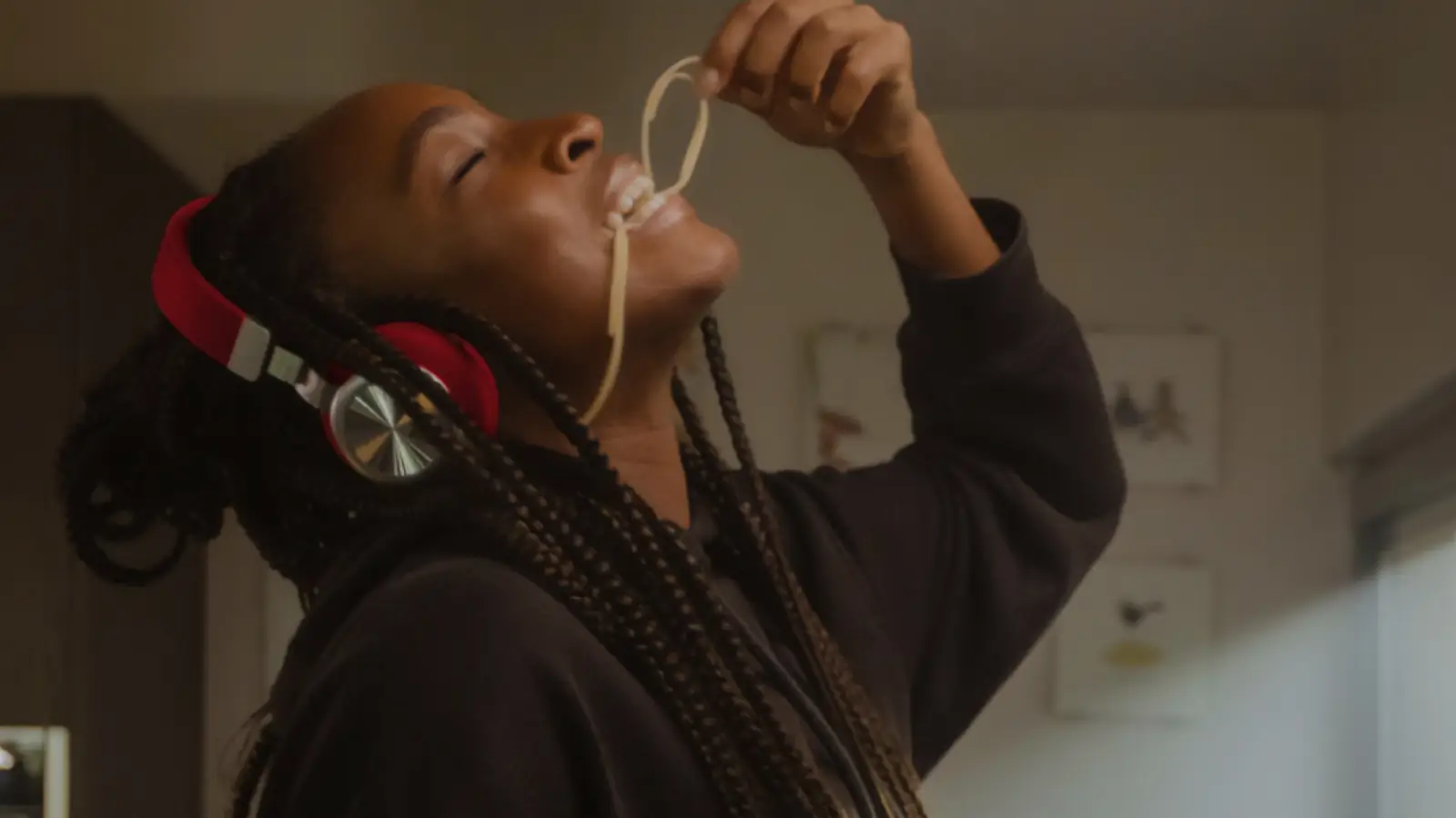 Woman in red headphones enjoying eating spaghetti with her fingers.