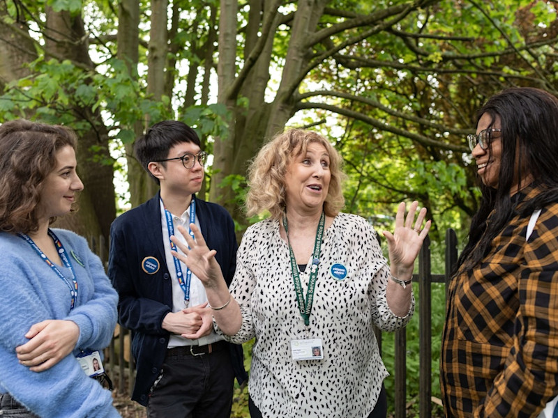 A group of 4 Citizens Advice volunteers together. One is talking to the others and they're all smiling.
