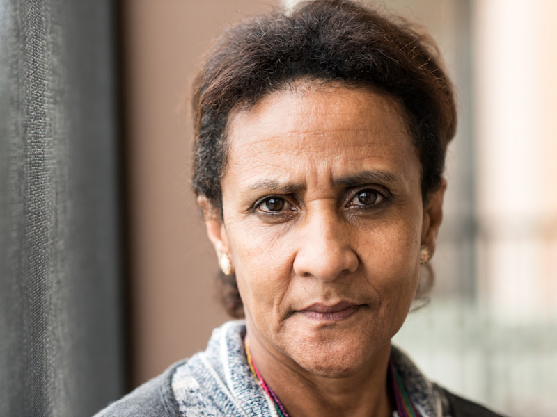 A close up of a middle-aged woman looking directly into the camera. She looks worried.