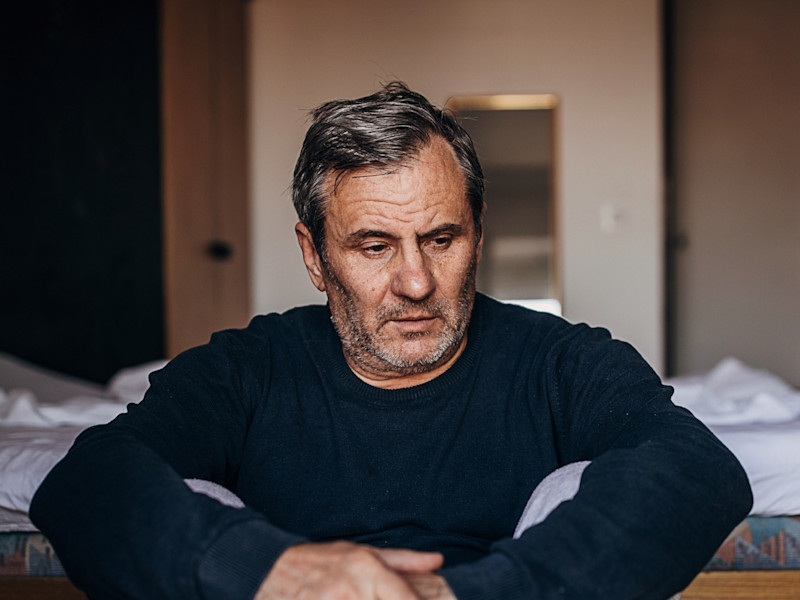 Man sitting with his hands crossed looking anxiously away from the camera