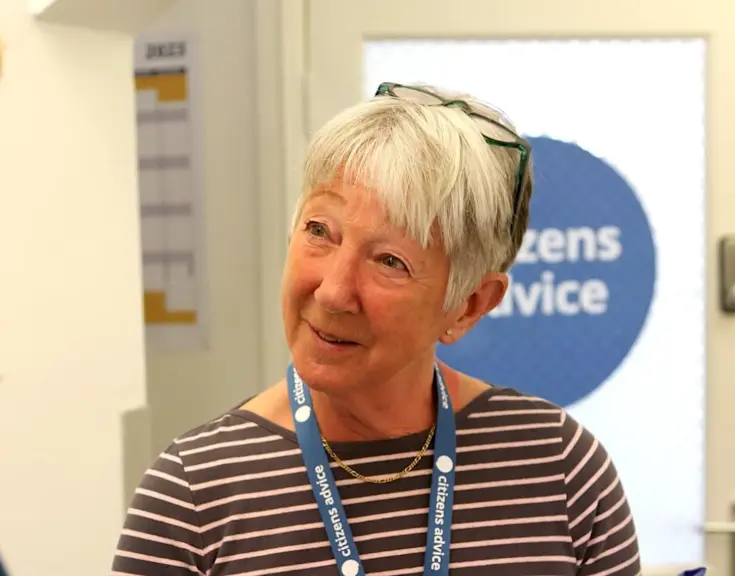 An adviser wearing a Citizens Advice lanyard talks to a blonde woman in a hallway