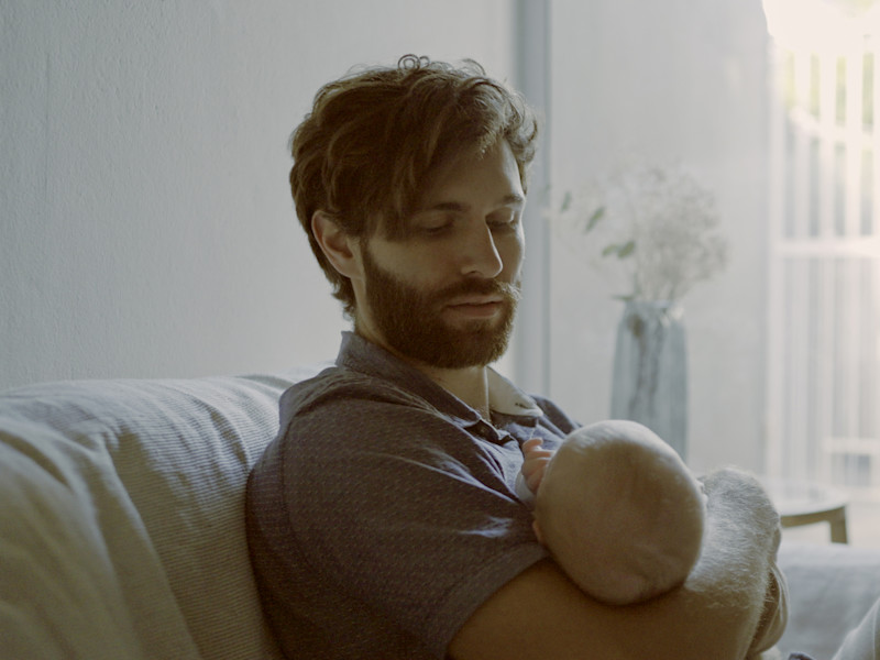 man sitting down holding baby