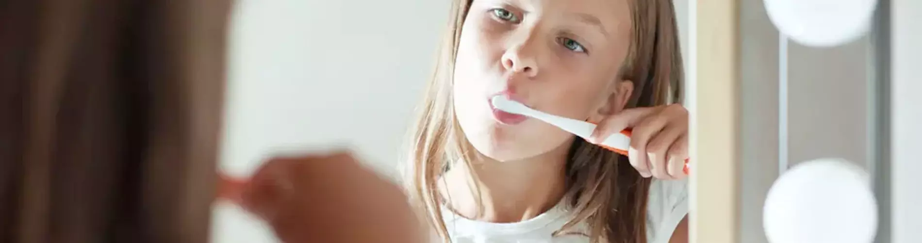 Girl Brushing her Teeth in Mirror