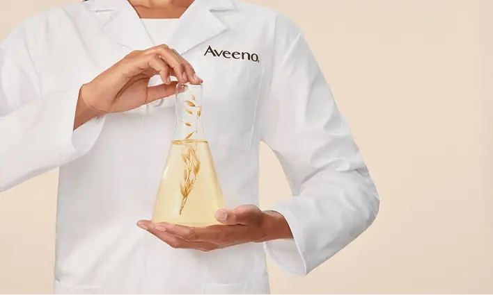 Aveeno scientist showcasing oat extract in a lab flask for skincare innovation.