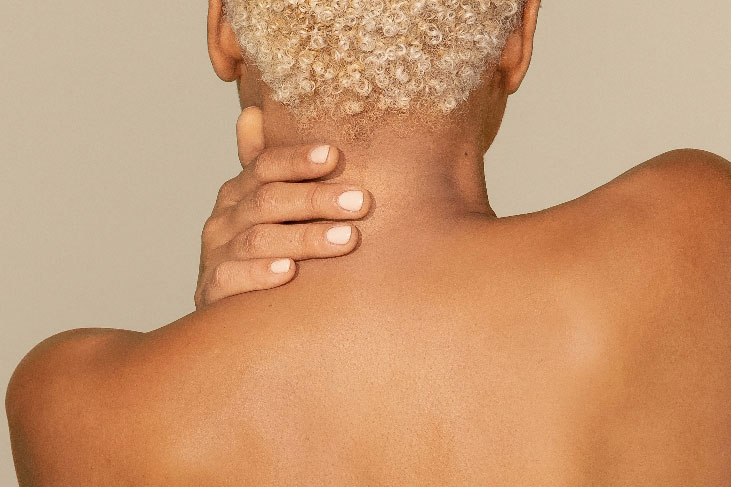 Woman's bare shoulders with hand on neck