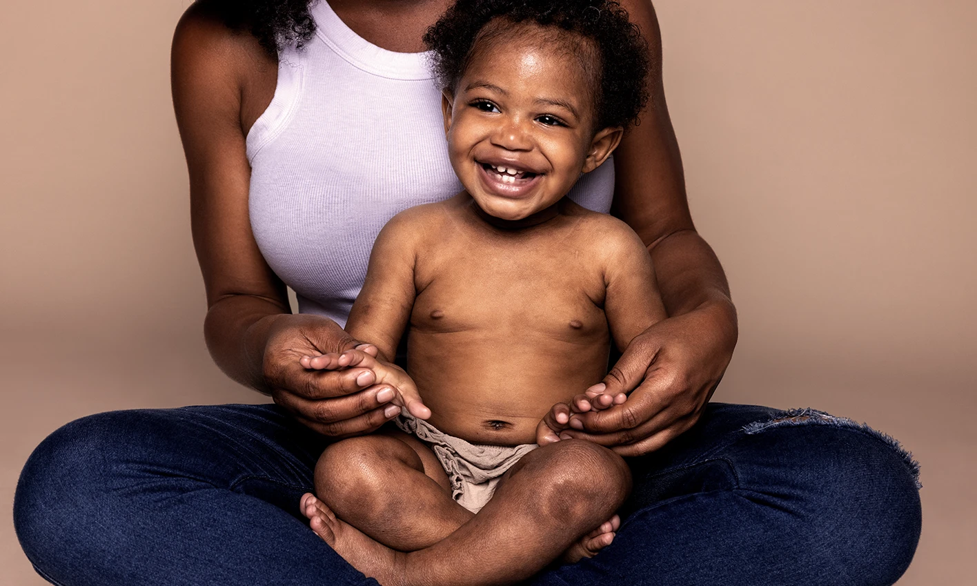 A joyful woman cradles a baby, both sharing a moment of happiness