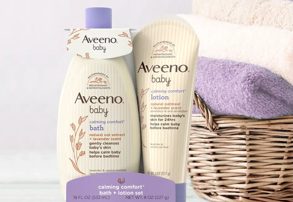 Aveeno® Baby Calming Comfort® Bath + Lotion Set next to a basket with 3 different colored towels