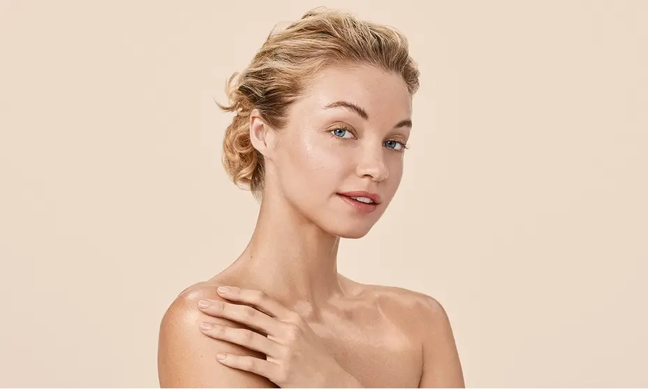 Blonde woman with blue eyes smiling, representing natural beauty.