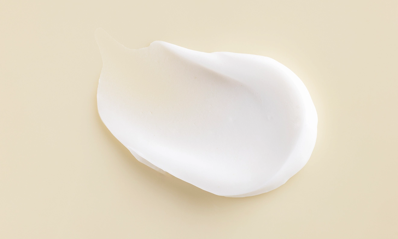 A delicate white cream positioned on a white surface showcasing its soft texture and uniform color