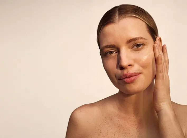 Woman with freckles on her face, smiling softly, showcasing her natural beauty and warm expression