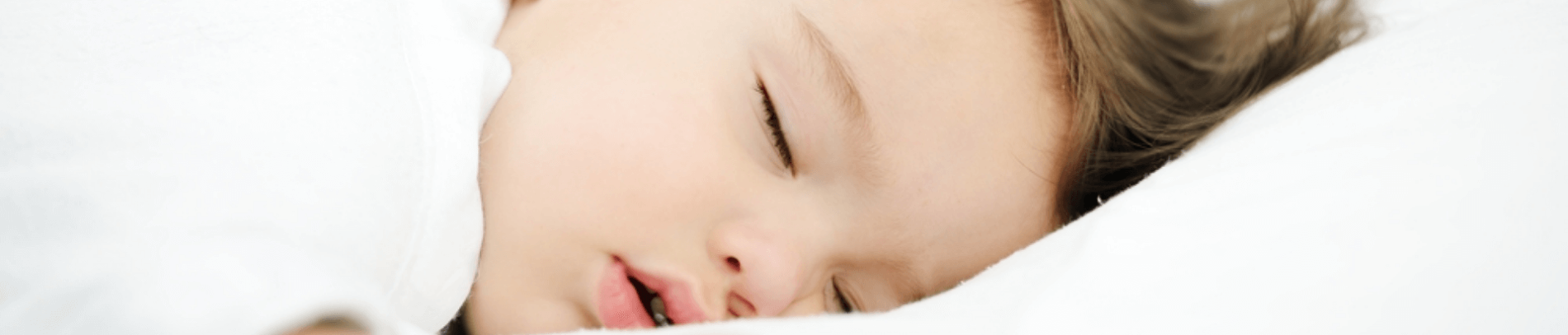 Toddler sleeping surrounded by white sheets