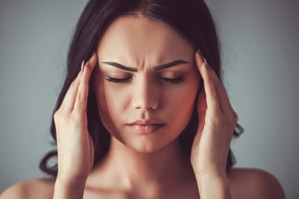 Woman suffering from skin conditions caused by stress itching her back.
