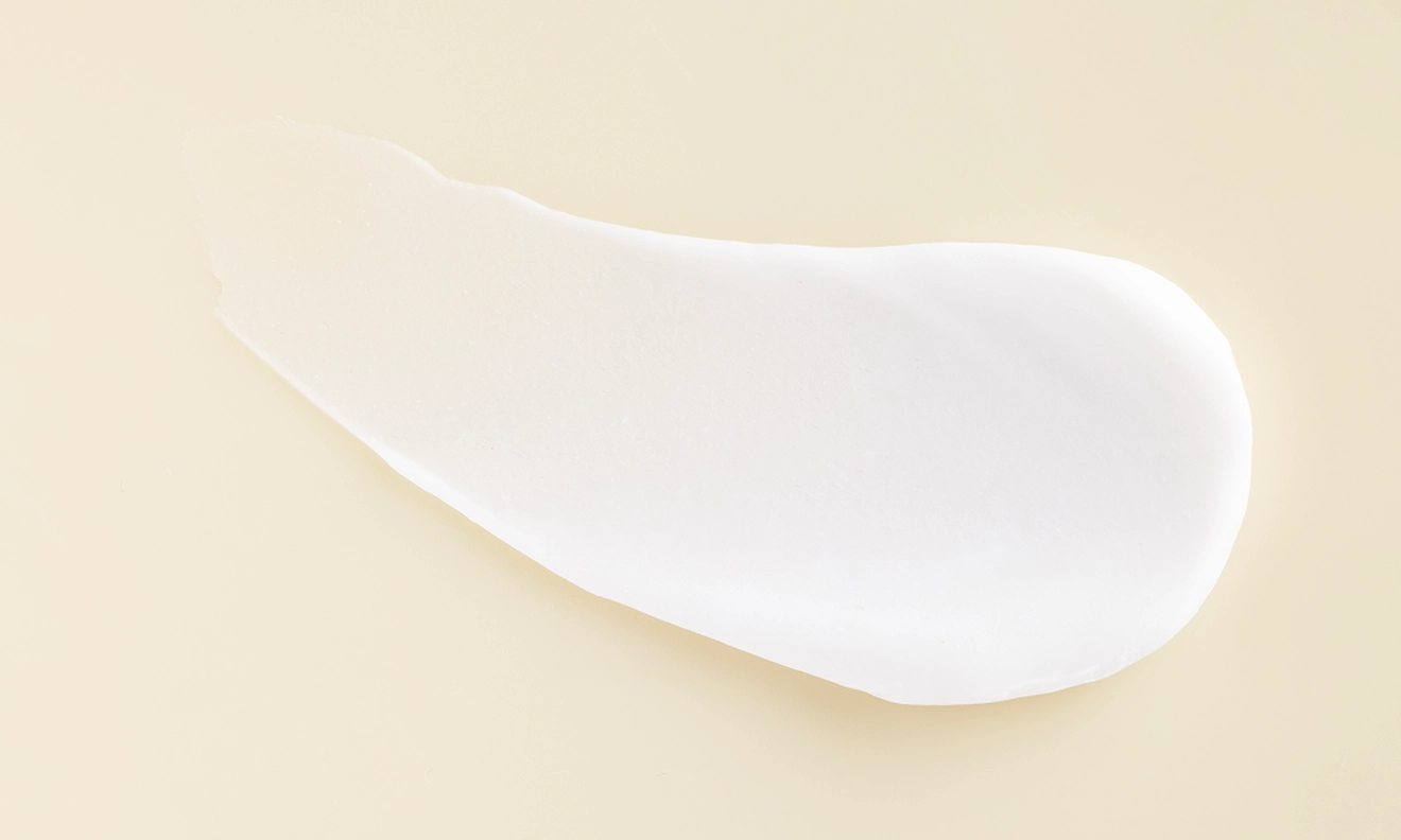 A delicate white cream positioned on a white surface showcasing its soft texture and uniform color