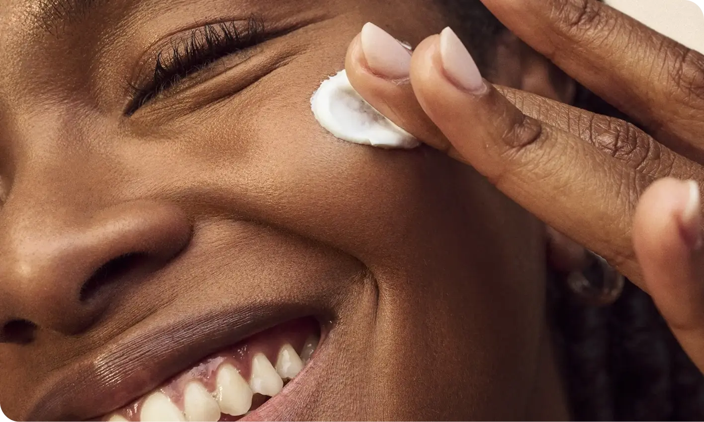 Sensitive skin tips, a woman with a cheerful smile applying cream on her face.