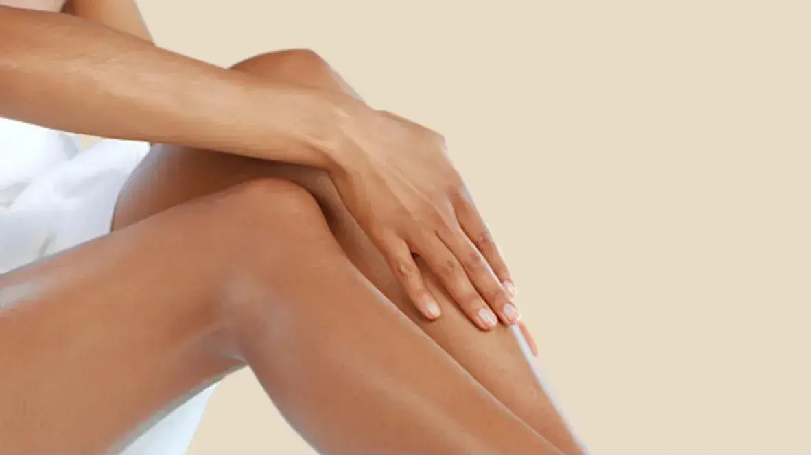 A woman gently touching her legs which appear to be moisturized
