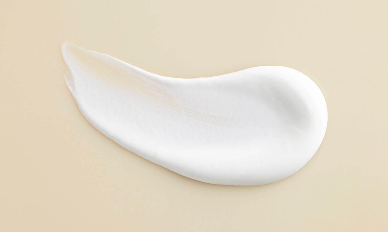 A delicate white cream positioned on a white surface showcasing its soft texture and uniform color