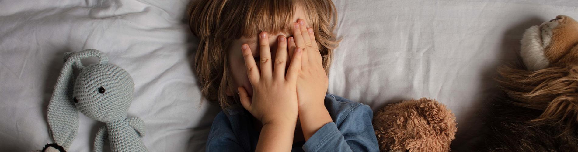 Boy covering his face in bed