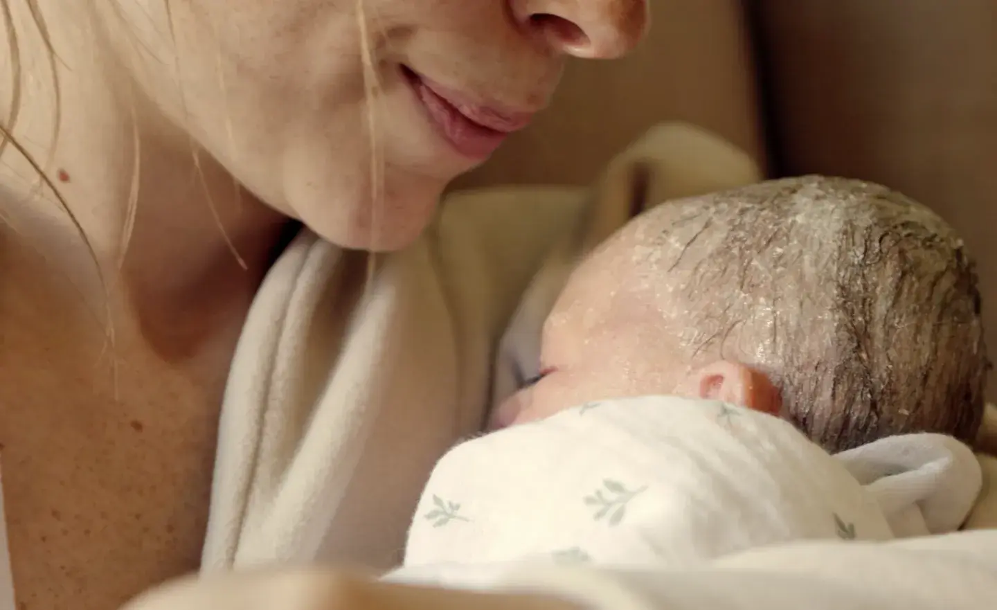 close up of woman holding newborn baby with vernix on their head