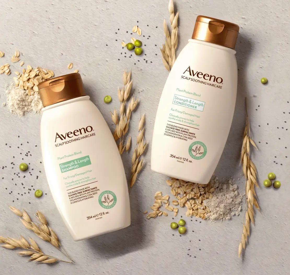 Aveeno® Strength & Length haircare set displayed with its nourishing ingredients for frizz control