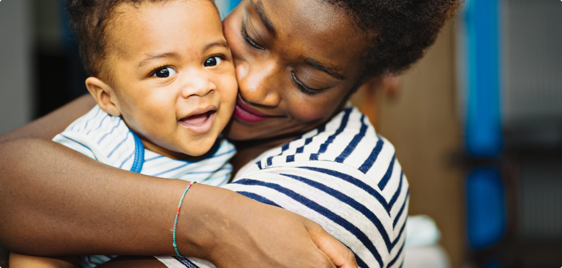 woman with curly hair holding smiling baby with curly hair