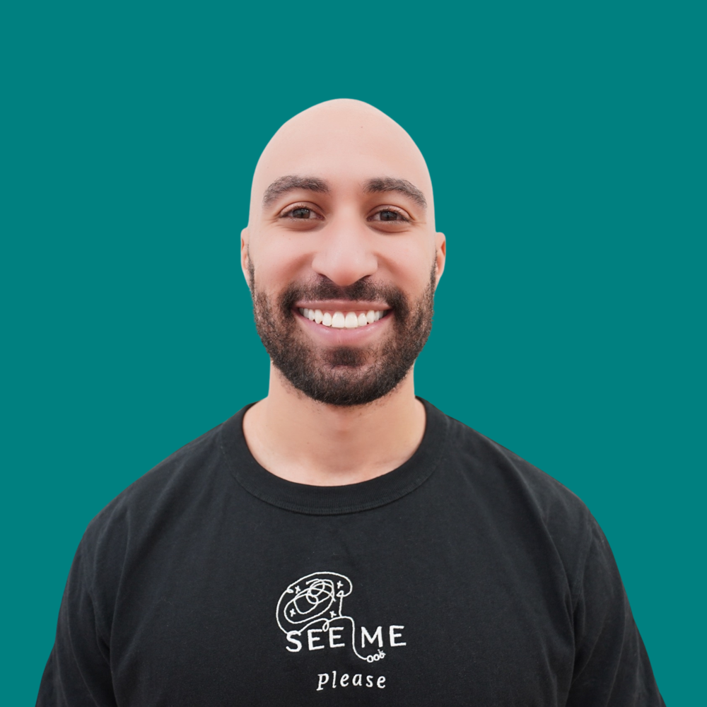 Stephan Morris, Software Engineer, dark beard, smiling in a black See Me Please embroidered t-shirt