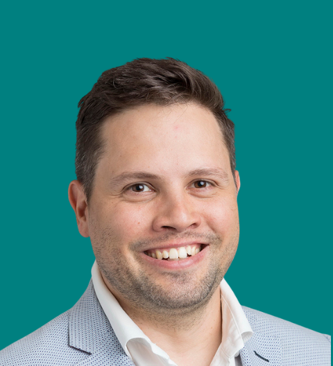 Profile photo of Alex – he has short brown hair, is wearing a light blue suit jacket with a white shirt.