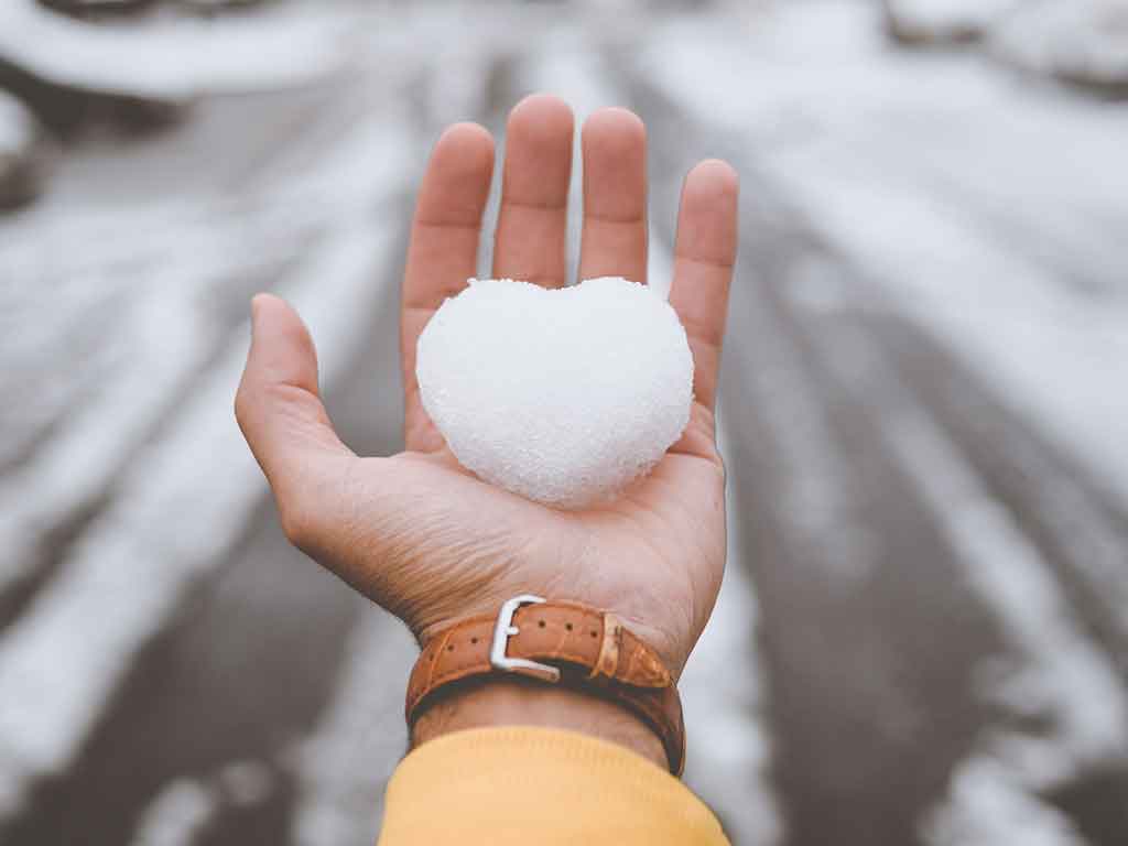 A hand holding a snowball. Photo by Clay Banks on Unsplash.